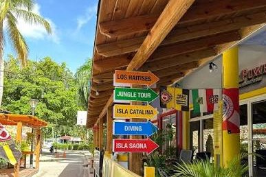 Letreros de excursiones a Isla Saona, Isla Catalina y buceo en la fachada de un comercio cerca de Dominicus